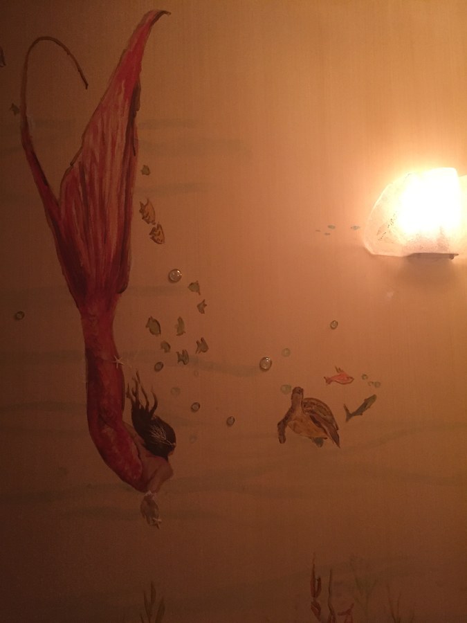 Red-tailed mermaid mural detail beside a wall sconce, Palm Beach, FL