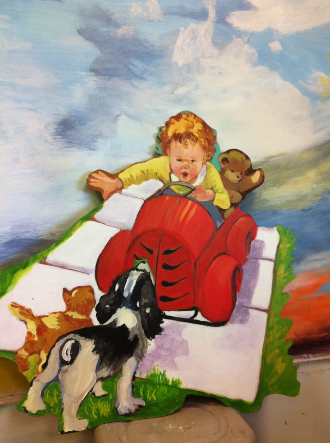 Companion painted cutout of a toddler in a red wagon with a teddy bear and dogs, Palm Beach, FL