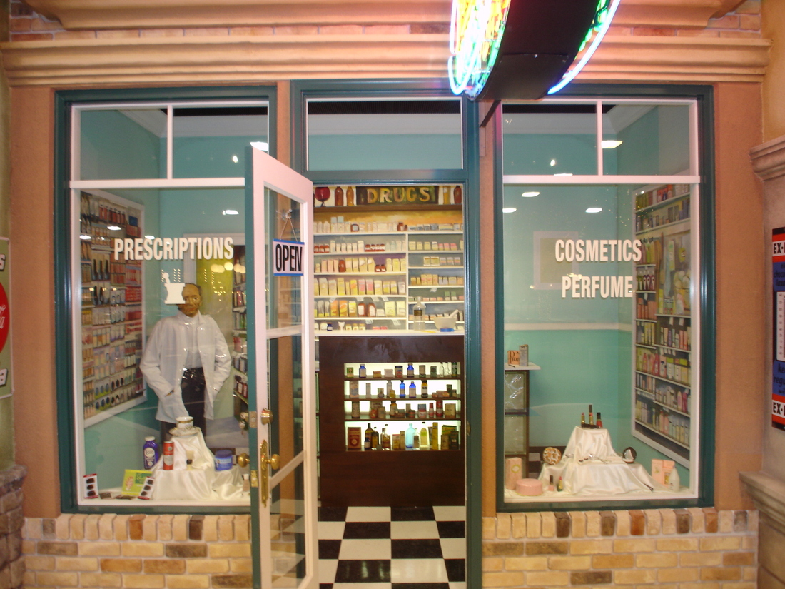 Pharmacy storefront facade mural with prescriptions and cosmetics signage, car museum backdrop, Palm Beach, FL