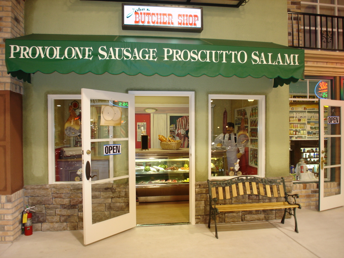 Italian deli storefront mural with sausage and salami signage, car museum backdrop, Palm Beach, FL