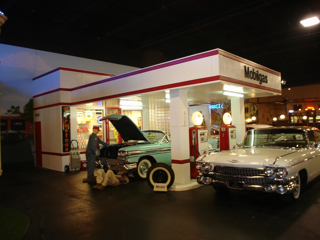 Night mural view of a vintage gas station with a painted mechanic beside a classic car, Palm Beach, FL