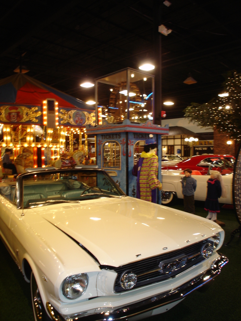 Night showroom view with a classic car parked in front of the painted streetscape mural, Palm Beach, FL