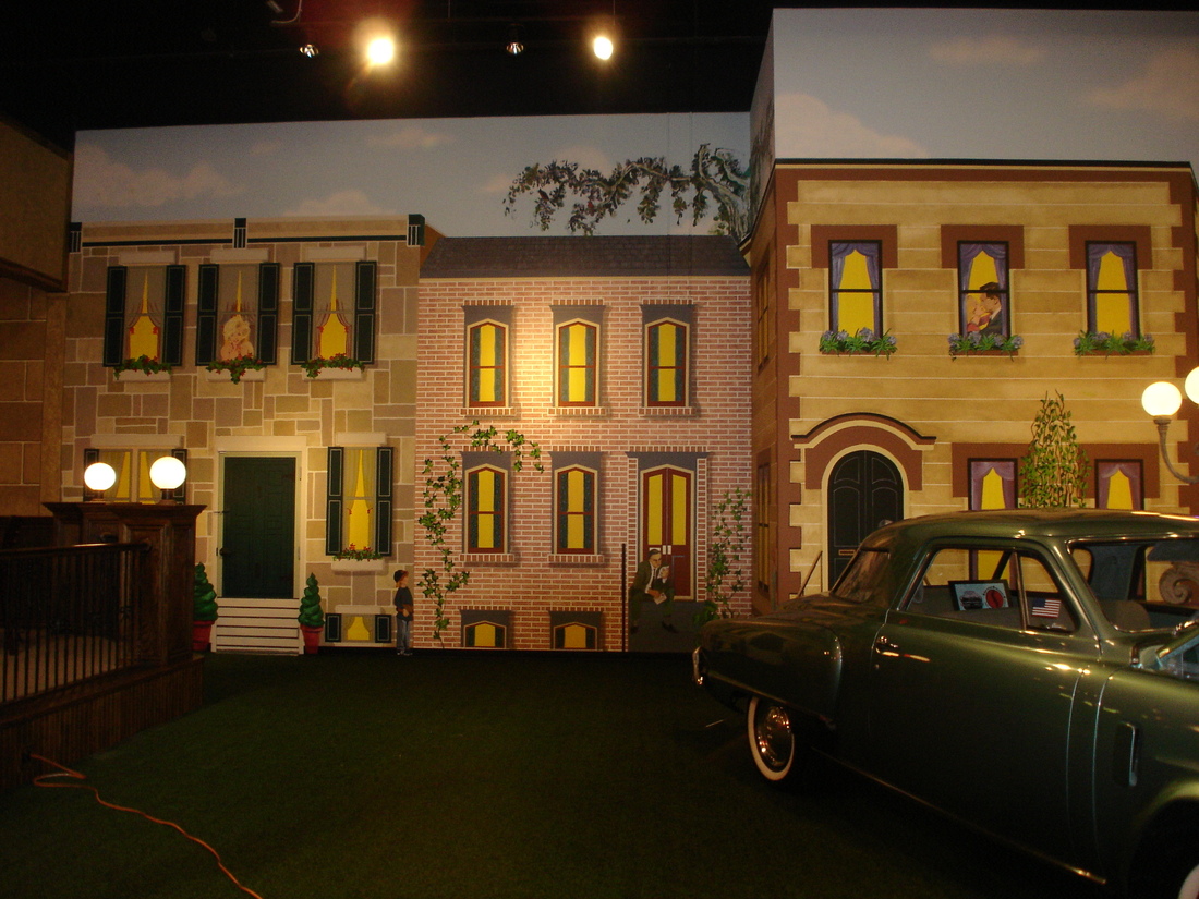 Wide night view of the brick building facade mural with parked vintage cars, car museum, Palm Beach, FL