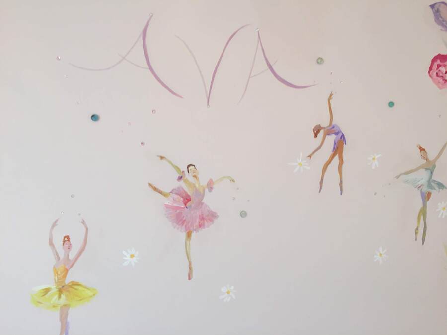 Two ballerinas in pink and yellow tutus dancing beneath ribbon and flower vines, close-up mural detail, Palm Beach, FL