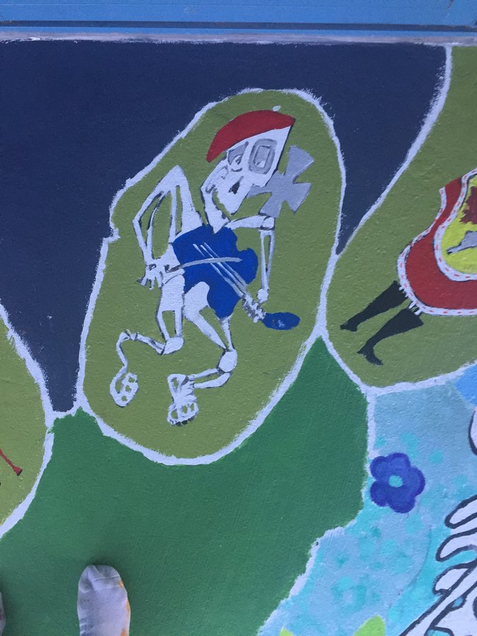 Skeleton figure in blue shorts running, second vignette view, exterior terrace mural, Palm Beach, FL