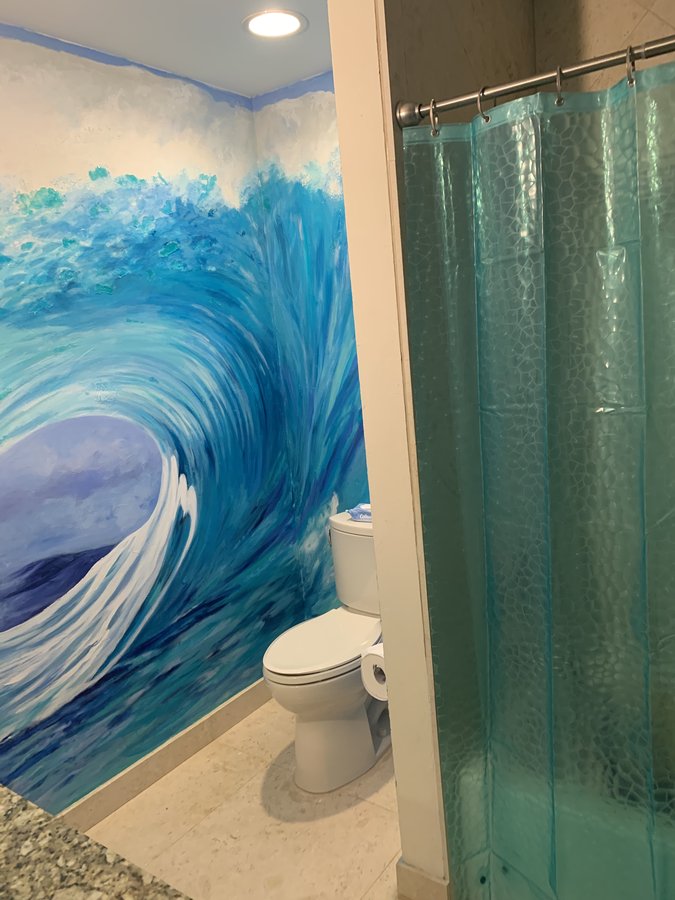 Ocean wave mural wide view above a bathroom shower curtain and toilet, Palm Beach, FL