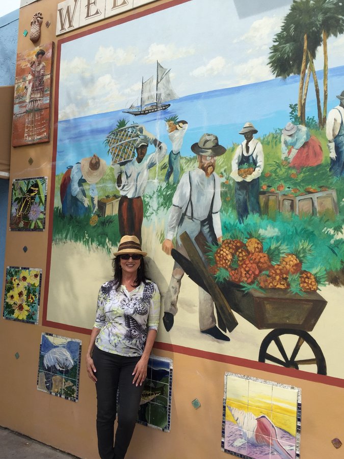 Full Stuart mural with a woman in a floral top posed at the base, Palm Beach, FL
