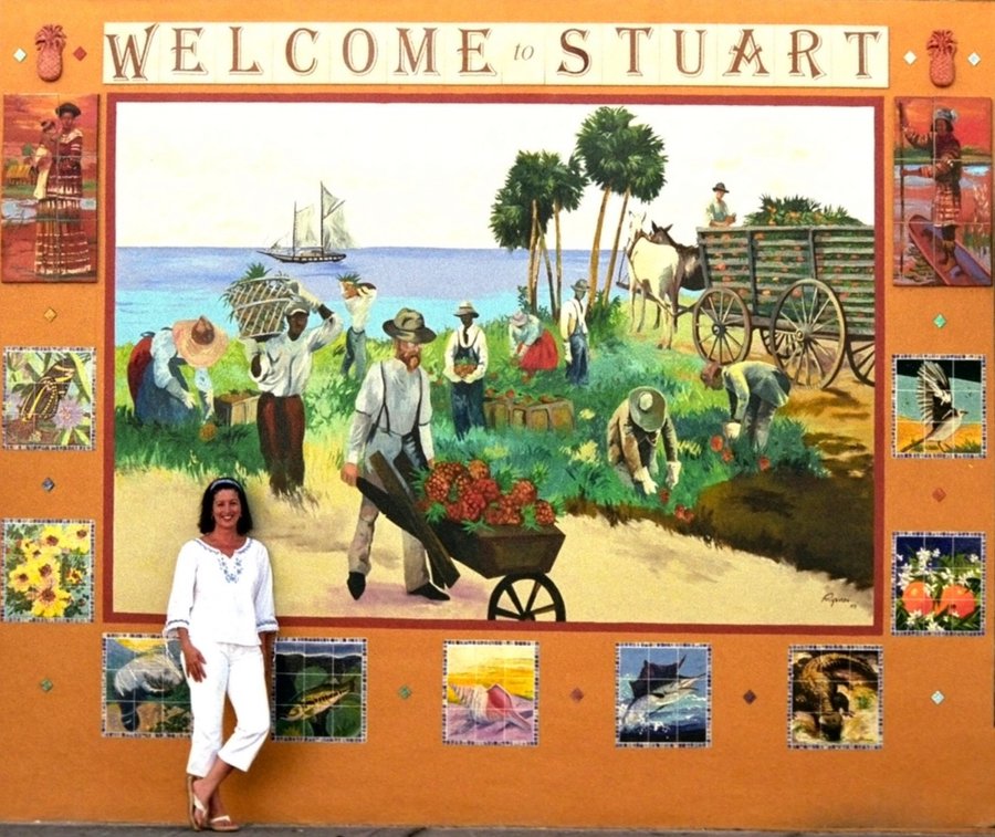 Full finished Stuart mural, woman posed in white beside the harvest scene, vivid daylight colors, Palm Beach, FL