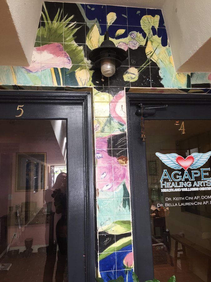 Hand-painted tile mural framing the Agape Healing Arts entrance, tropical florals in blue and pink, Palm Beach, FL