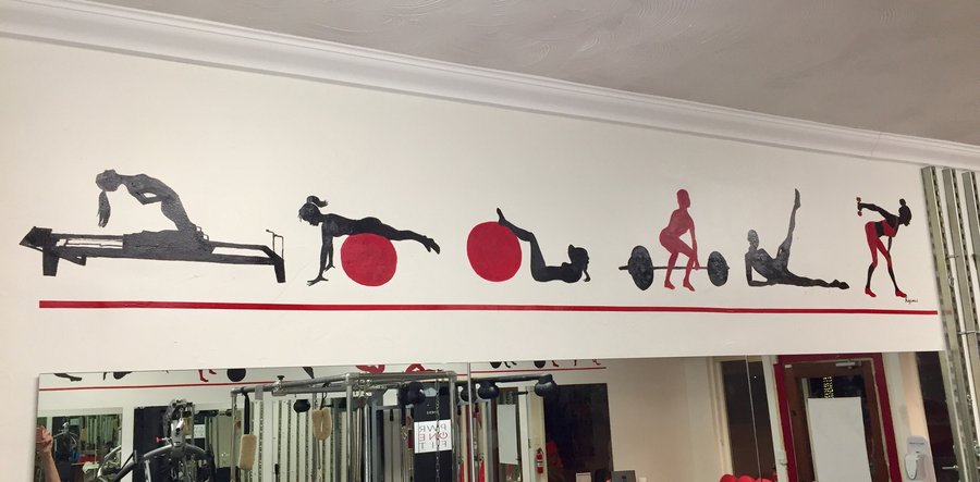 Full wide view of the exercise-silhouette border mural above the gym mirrors, red and black palette, Palm Beach, FL