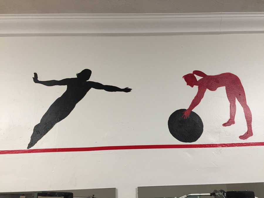 Plank and stability-ball silhouette figures painted along the gym mural border, Palm Beach, FL