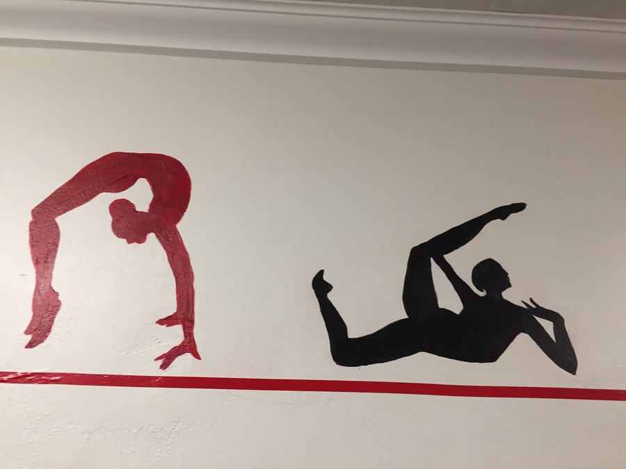 Kettlebell-swing silhouette figures painted along the gym mural border, Palm Beach, FL