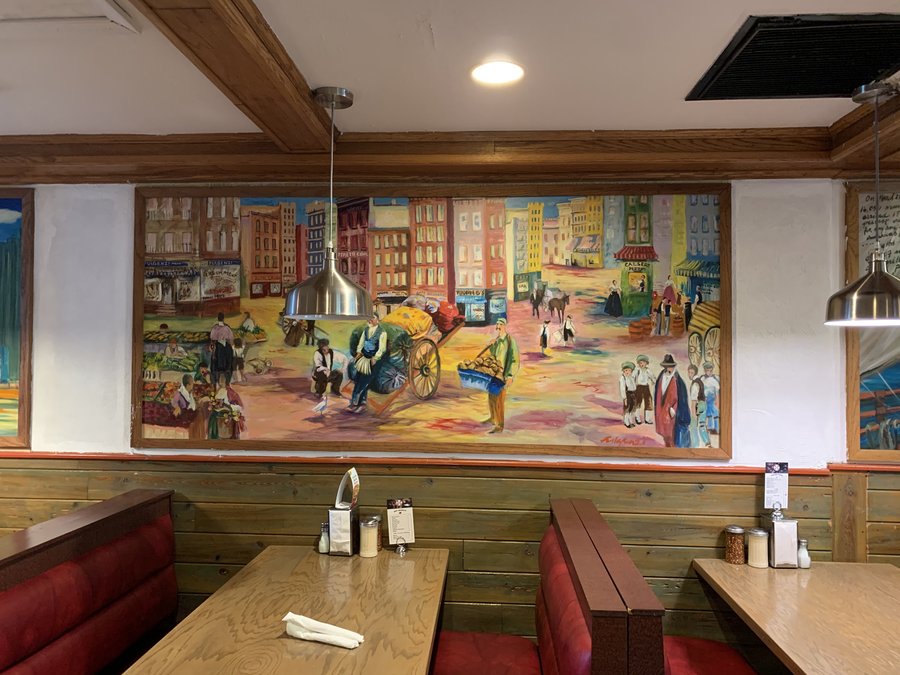 Wide view of the Ellis Island arrival mural panel above the restaurant booths, Palm Beach, FL