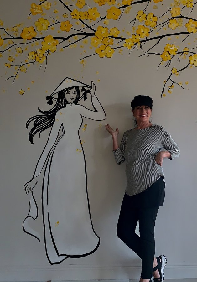 Artist posed beside the finished ao dai figure and cherry blossom tree mural, Pho and Rolls, Palm Beach, FL