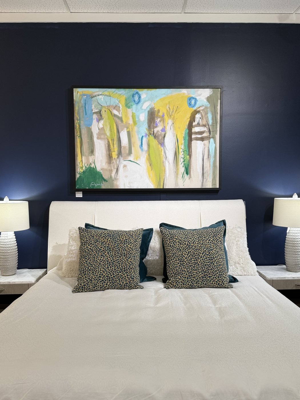 Abstract figures painting by Maureen Fulgenzi above a tufted white headboard in a navy-walled bedroom, Palm Beach, FL