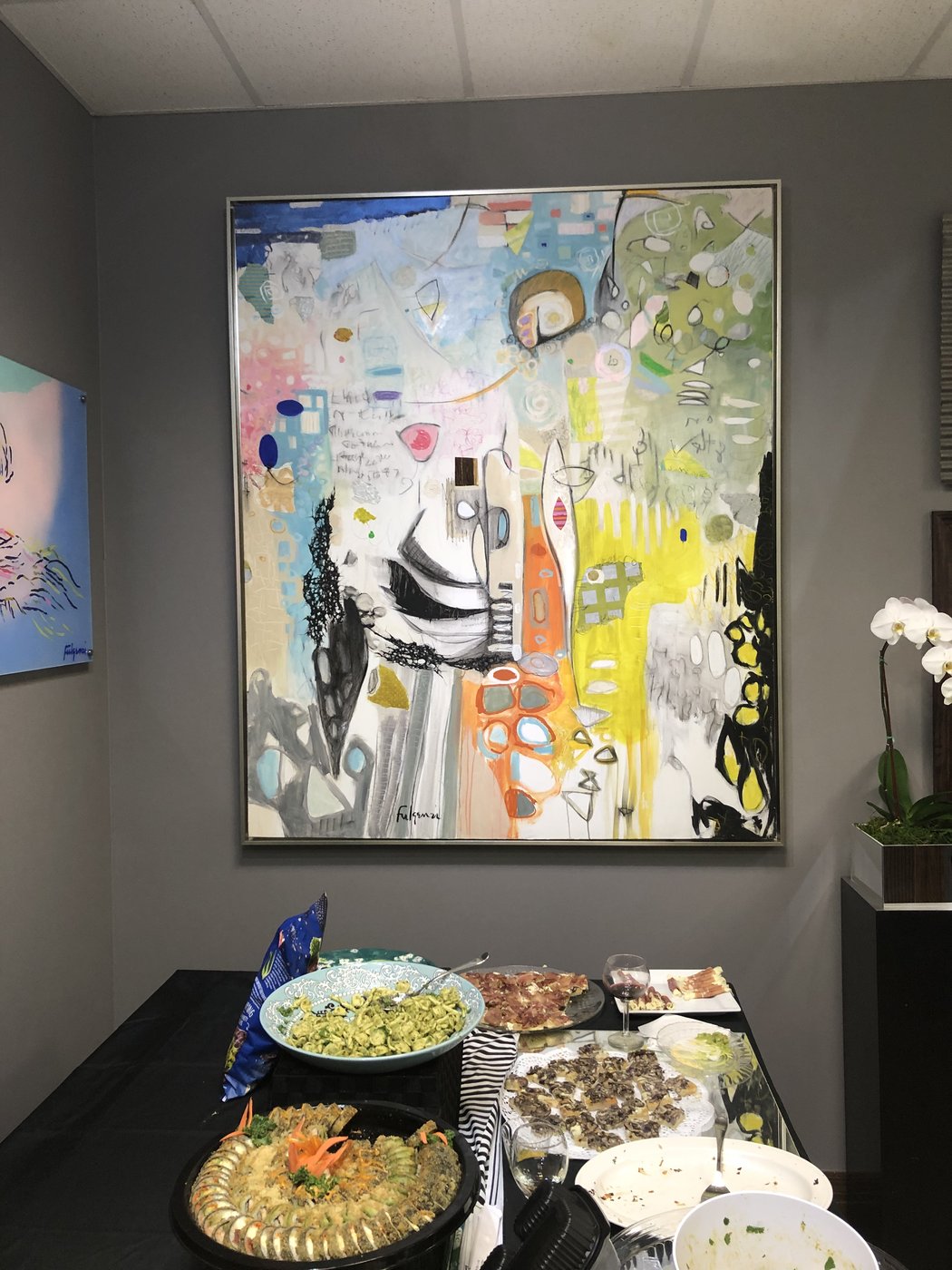 Three abstract paintings by Maureen Fulgenzi on a grey wall above a catered party table, Palm Beach, FL