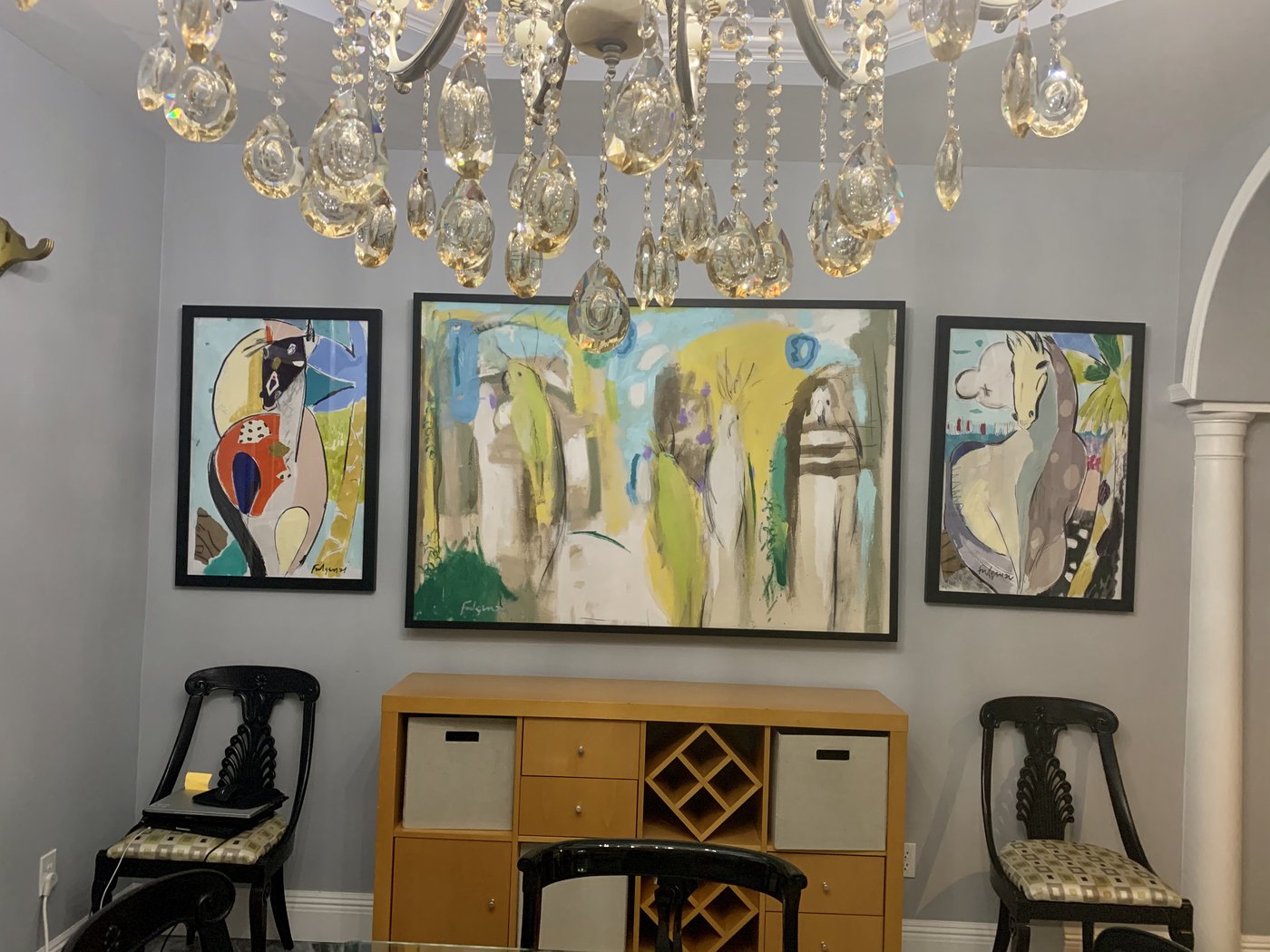 Three framed abstract paintings by Maureen Fulgenzi on a foyer gallery wall beneath a crystal chandelier, Palm Beach, FL